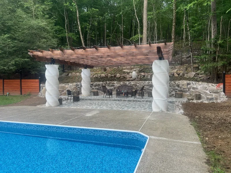 Finished printed concrete columns and shade structure beside a pool.