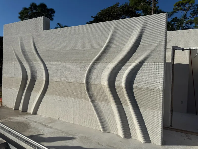 Printed concrete facade with deep vertical undulating waves running its full height.